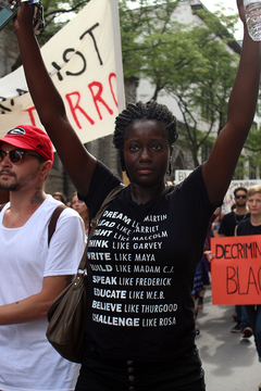 Jaleesa Potts, a Syracuse community member, walks emotionally with hands up as other protesters around her shout: 