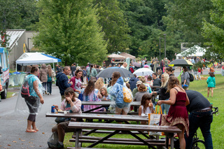 Visitors of the Golden Harvest Festival take a break from walking through the park to sit and enjoy the food they purchased from different vendors. Despite the rain people took advantage of the day to taste local restaurants and food trucks. 